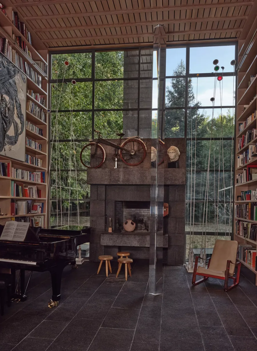 Christie's, Anthology of Design: library with grand piano, stone fireplace and a bicycle on the mantel