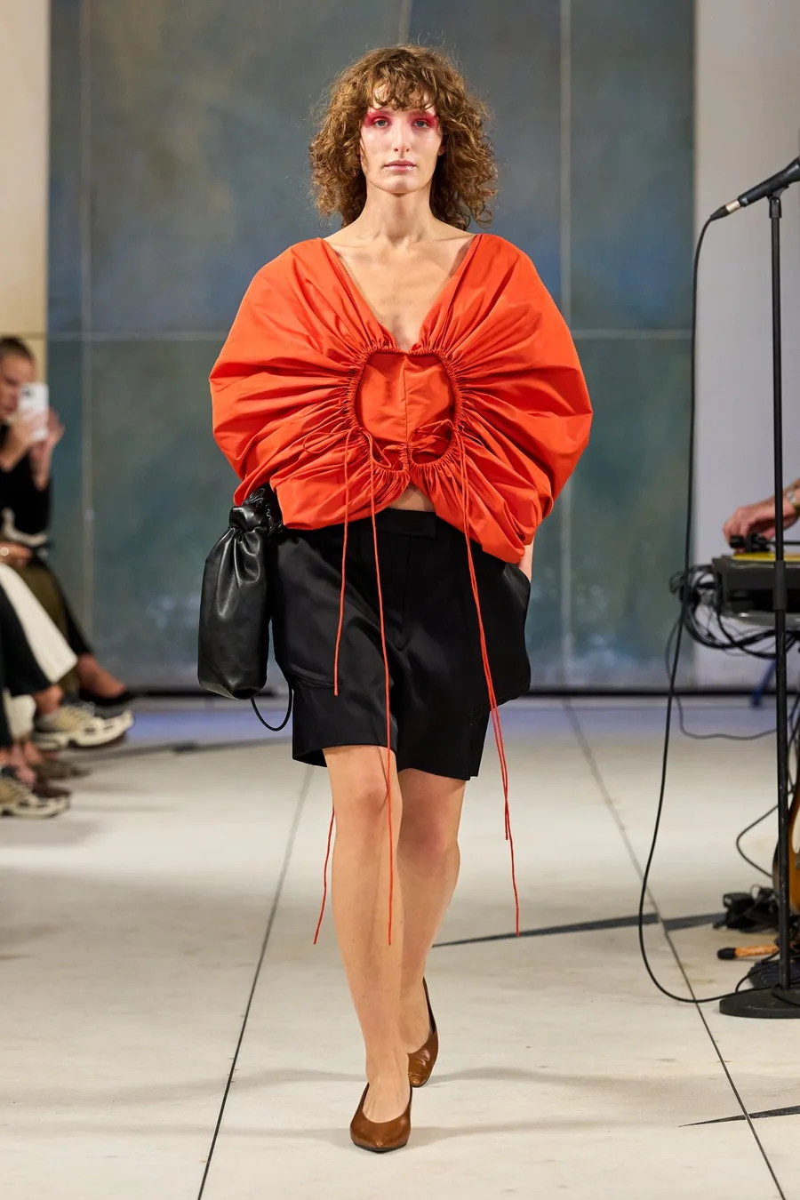 SHOWstudio, Litkovska S/S 27 STRICHA: model in a gathered orange top and black shorts with long ties