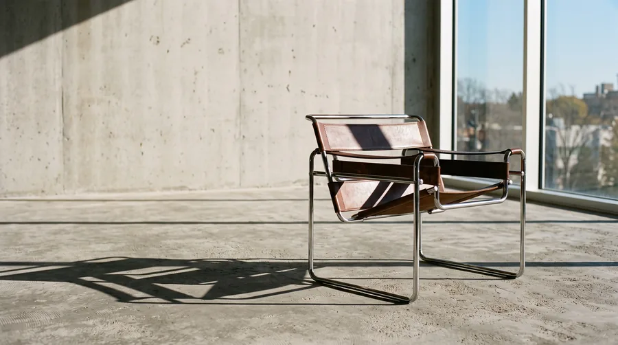 A single leather and steel lounge chair in an empty sunlit room